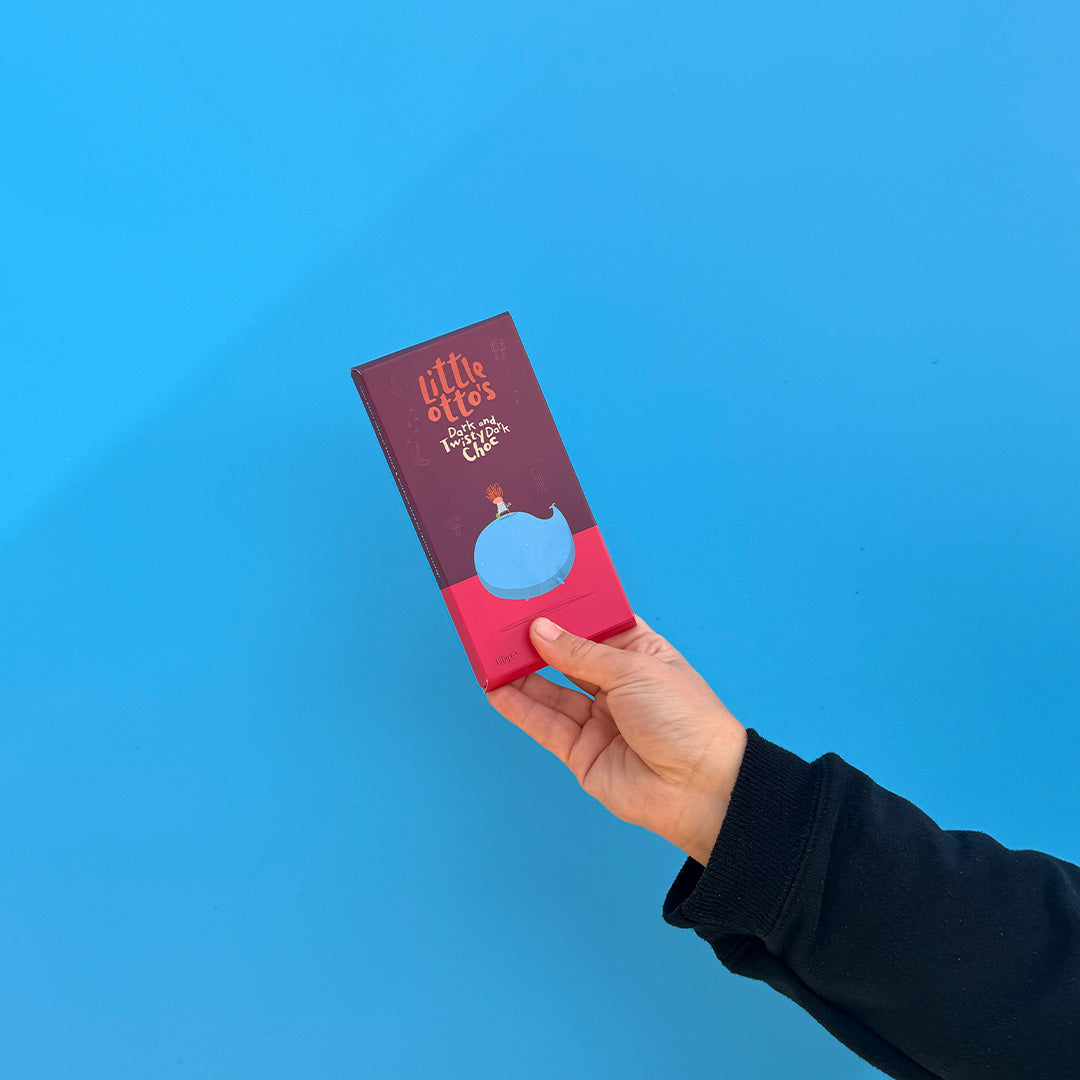 A hand wearing a black long-sleeve shirt holds a small book or notebook titled 'little offs' against a solid bright blue background.