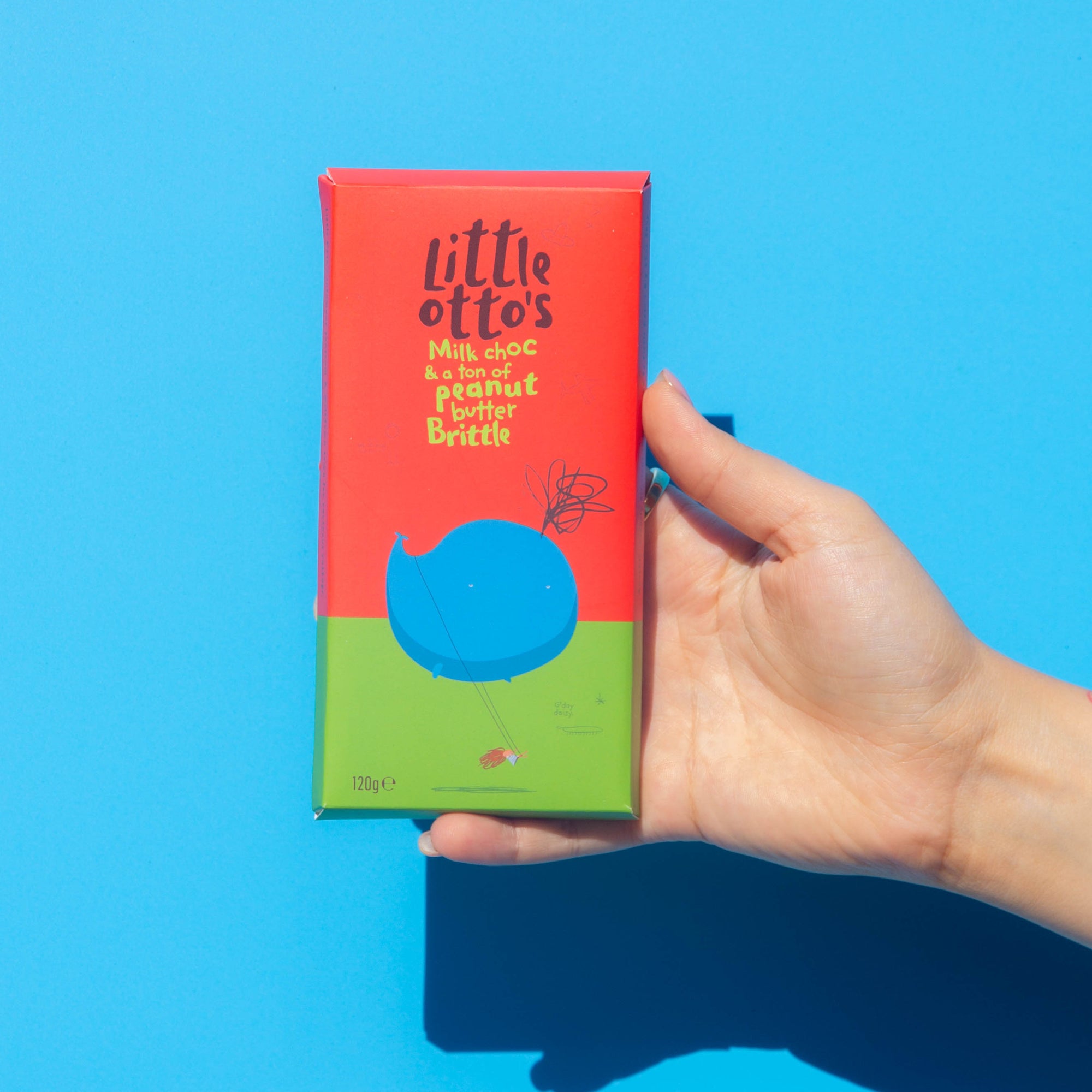 Little Otto's Chocolate bar Milk Chocolate Peanut Buttler Brittle Infront of Busselton blue wall