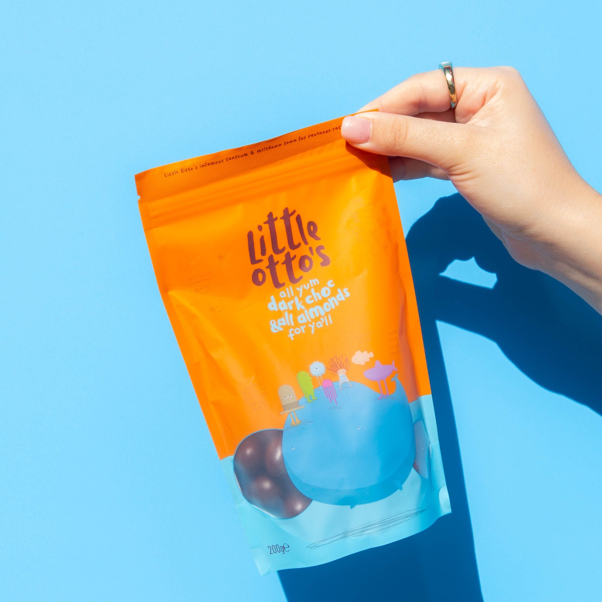 Little Otto's Staff holding  Dark Chocolate Almonds 200g infront of Busselton blue wall