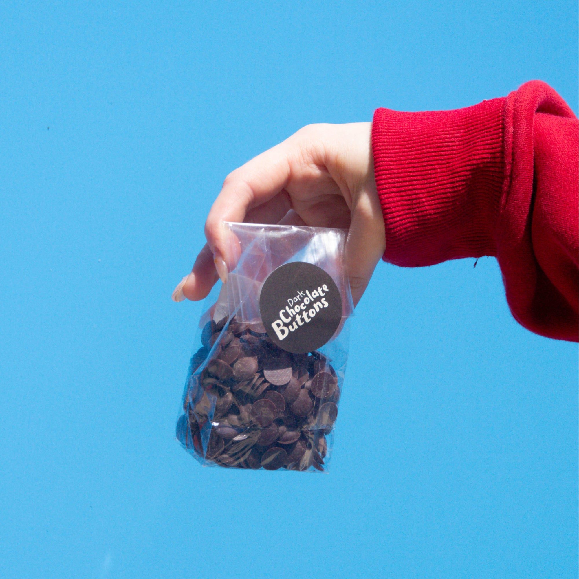 Little Otto's Staff holding Dark Chocolate Buttons 100g Infront of Busselton blue wall
