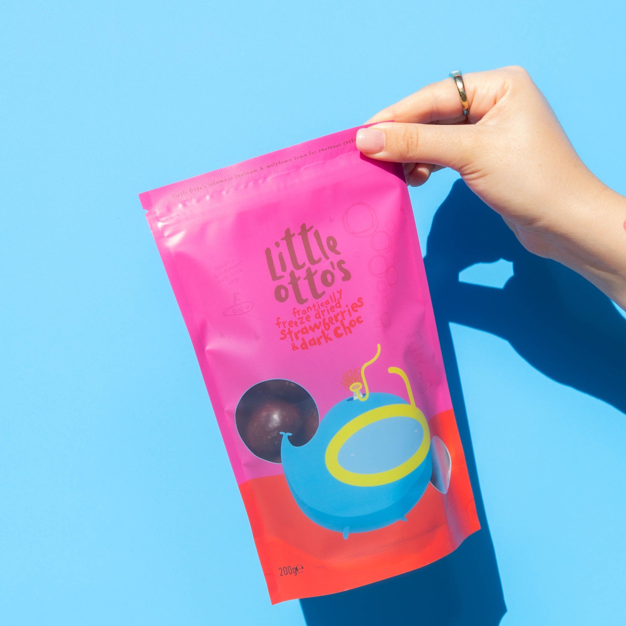 Little Otto's Staff holding Dark Chocolate Freeze Dried Strawberries 200g infront of Busselton blue wall