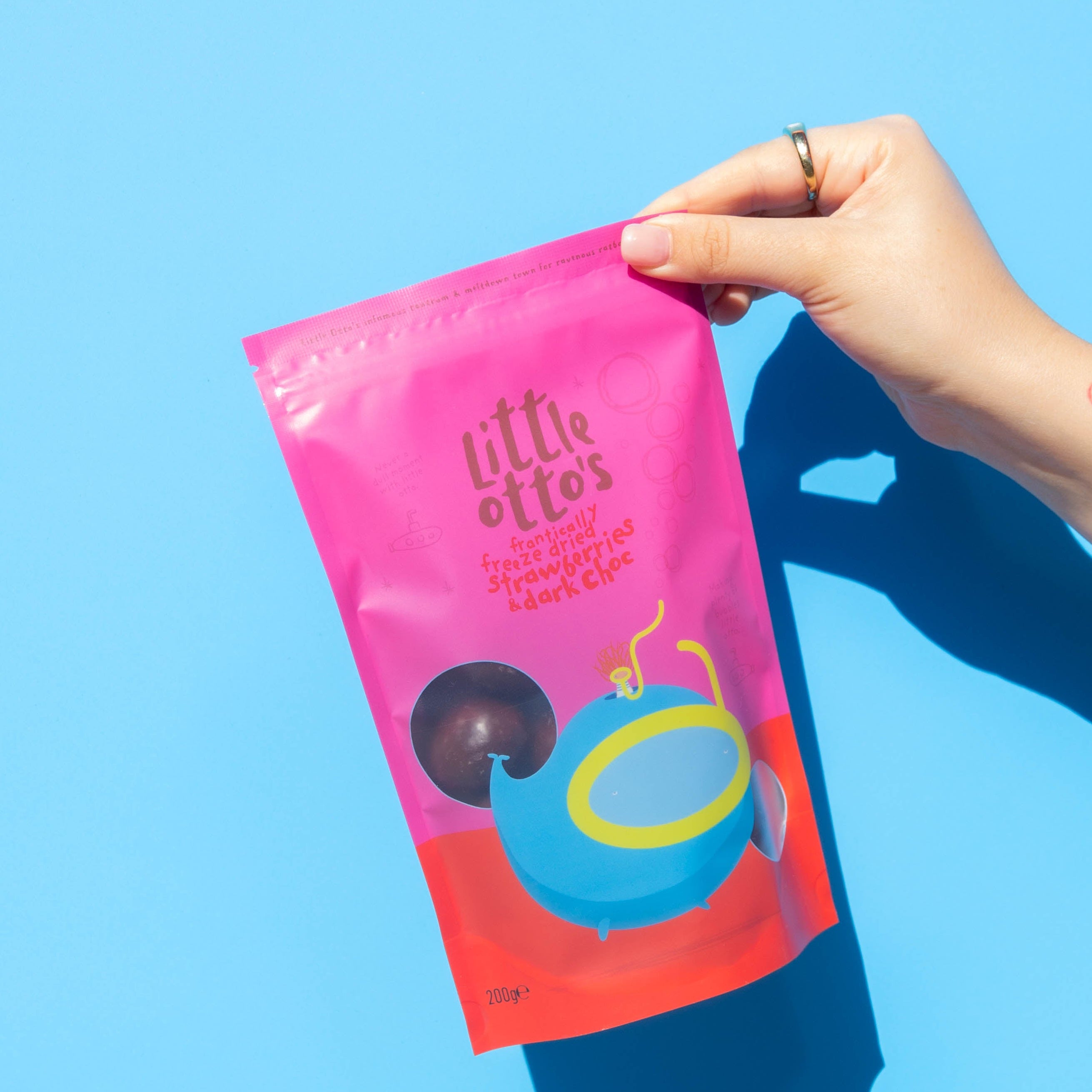 Little Otto's Staff holding Dark Chocolate Freeze Dried Strawberries 200g infront of Busselton blue wall
