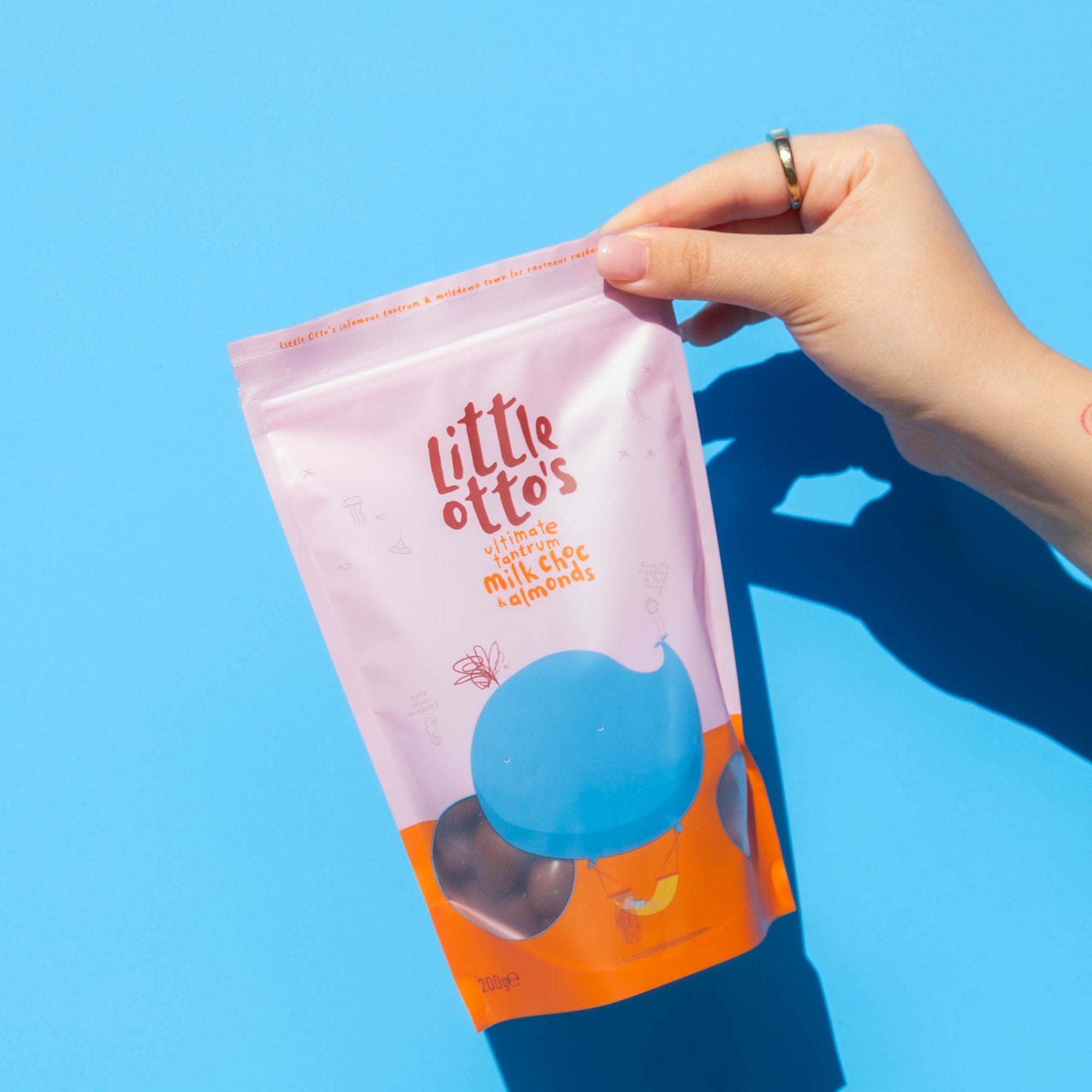 Little Otto's Staff holding Milk Chocolate Almonds 200g Infront of Busselton blue wall
