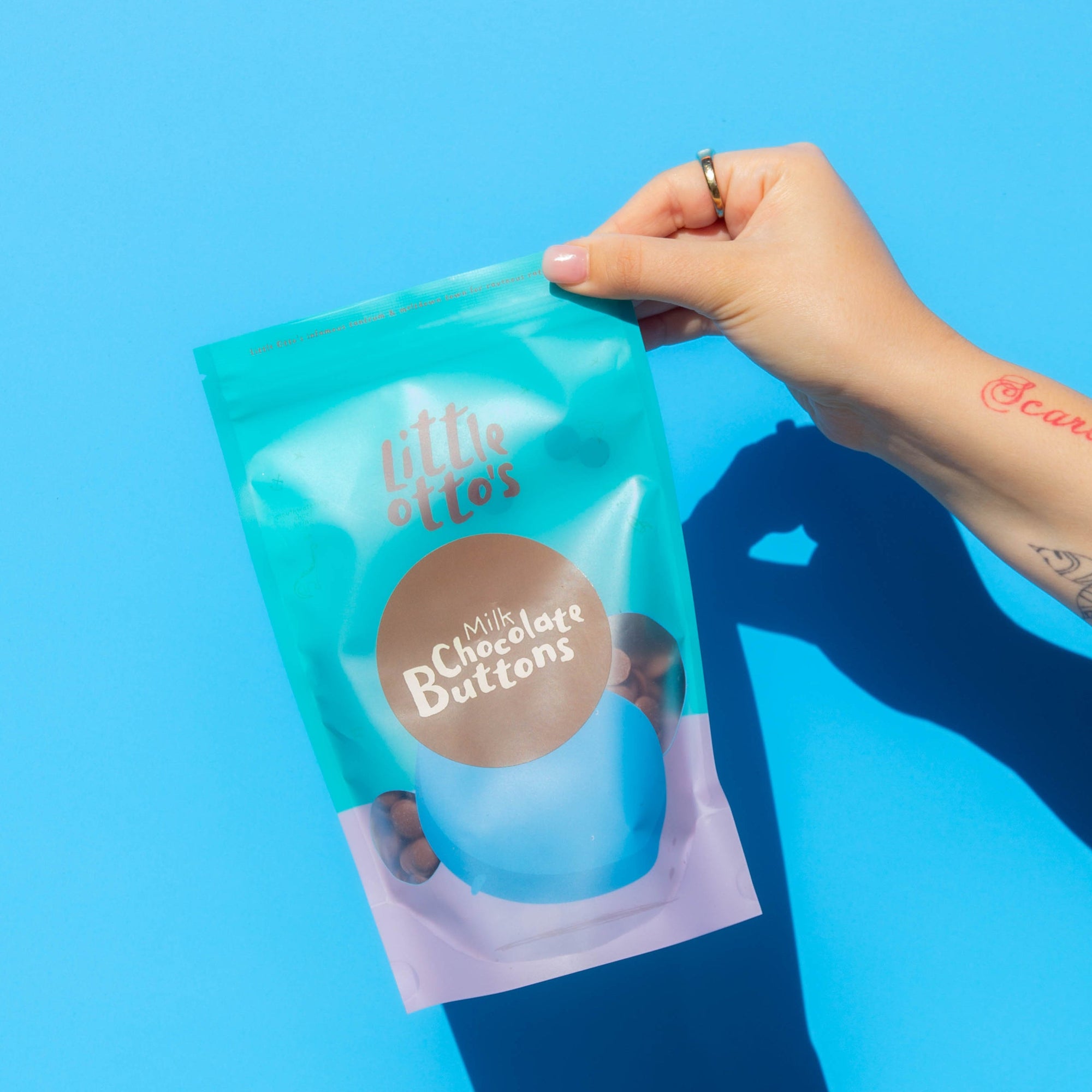 Little Otto's Staff holding Milk Chocolate Buttons 250g Infront of Busselton blue wall