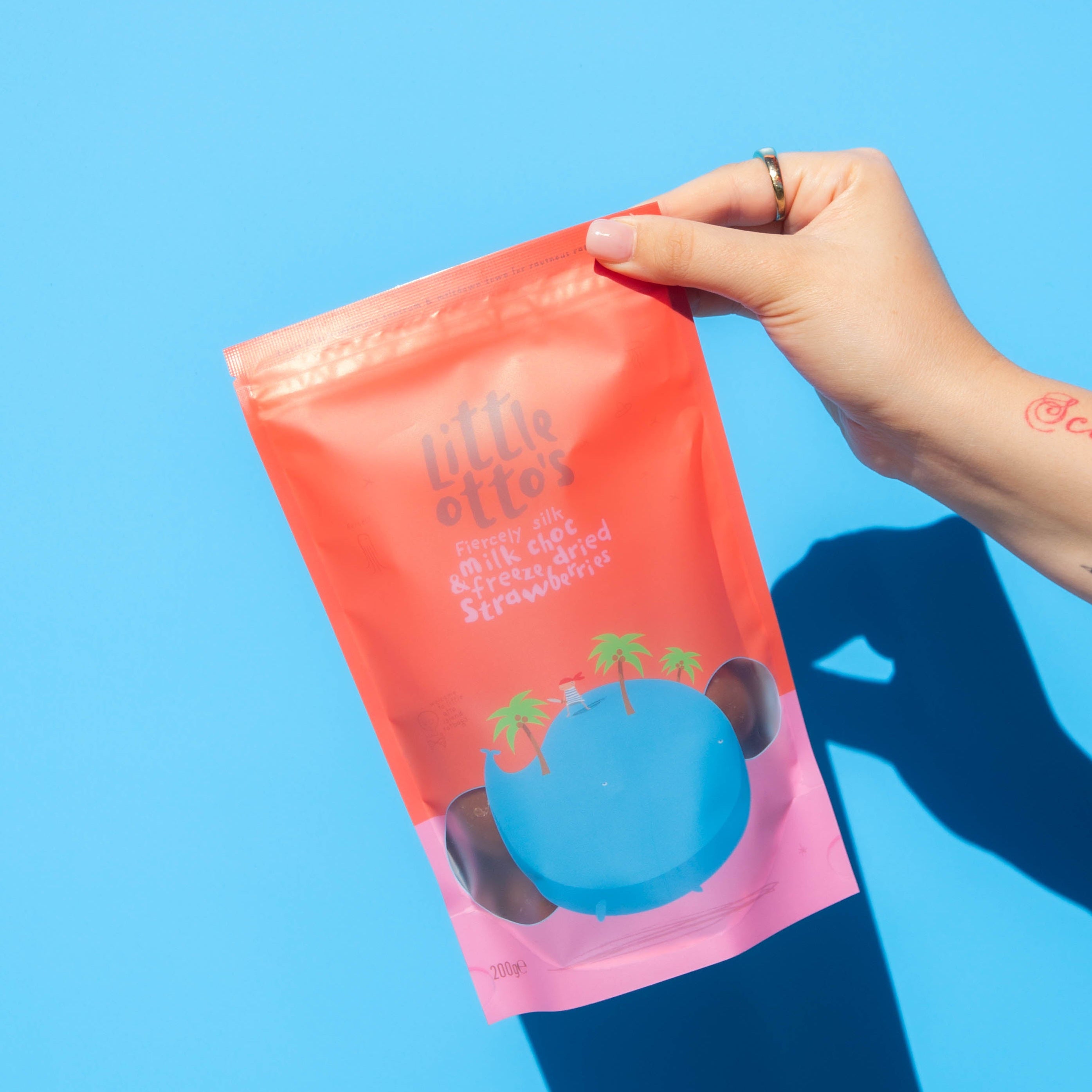 Little Otto's Staff holding Milk Chocolate Freeze Dried Strawberries 200g infront of Busselton blue wall