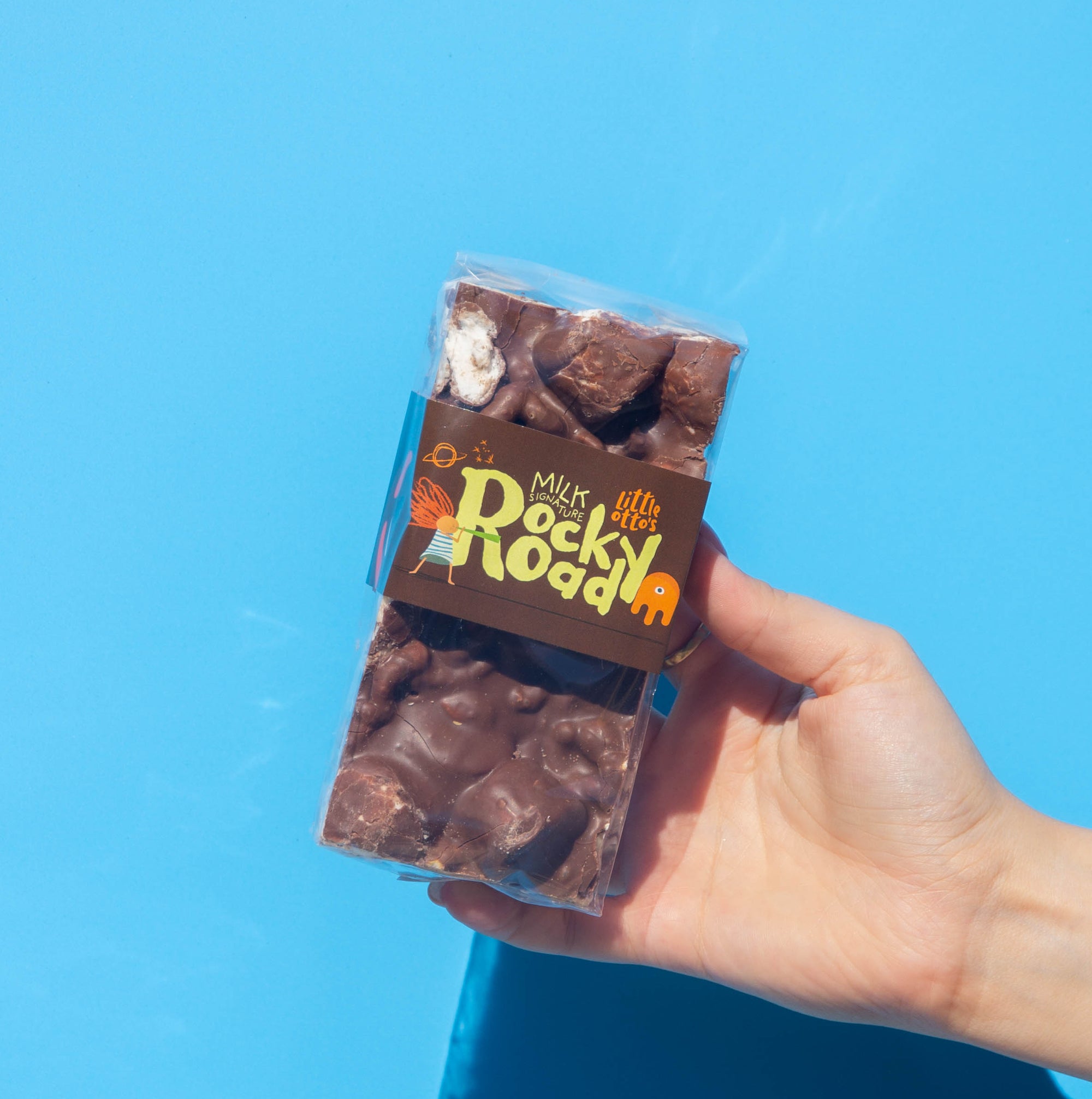 Little Otto's Milk Chocolate Signature Rocky Road 250g infront of Busselton blue wall