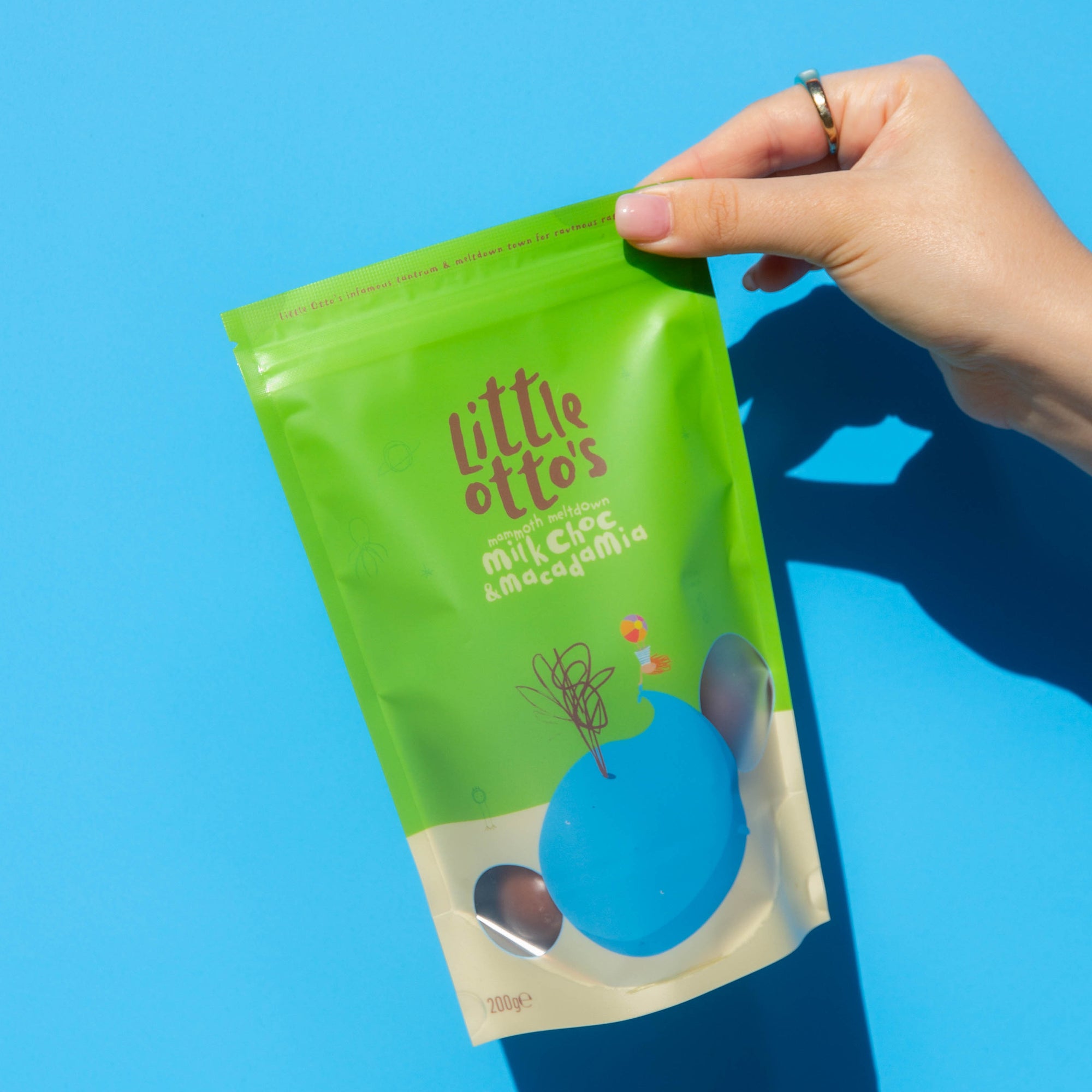 ittle Otto's Staff holding Milk Chocolate  and Macadamia 200g Infront of Busselton blue wall