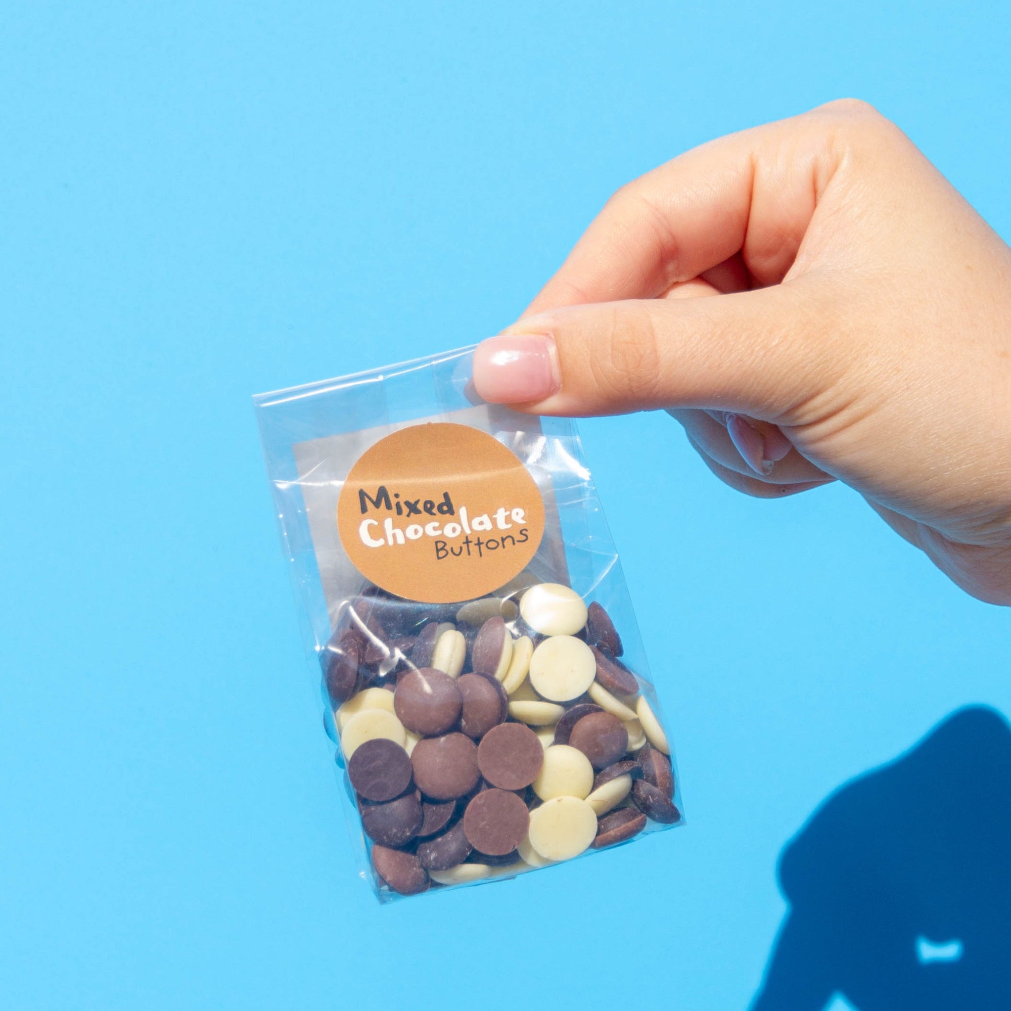Little Otto's Staff holding Mixed Chocolate Buttons 100g Infront of Busselton blue wall