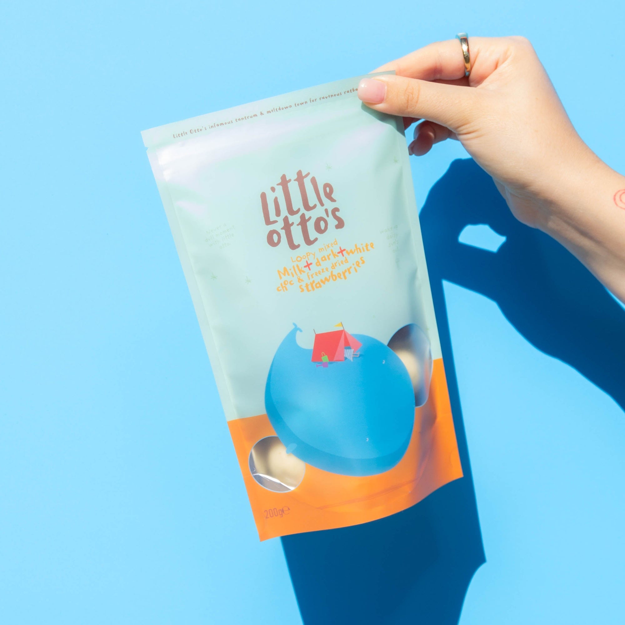 Little Otto's Staff holding Mixed Chocolate Freeze Dried Strawberries 200g infront of Busselton blue wall