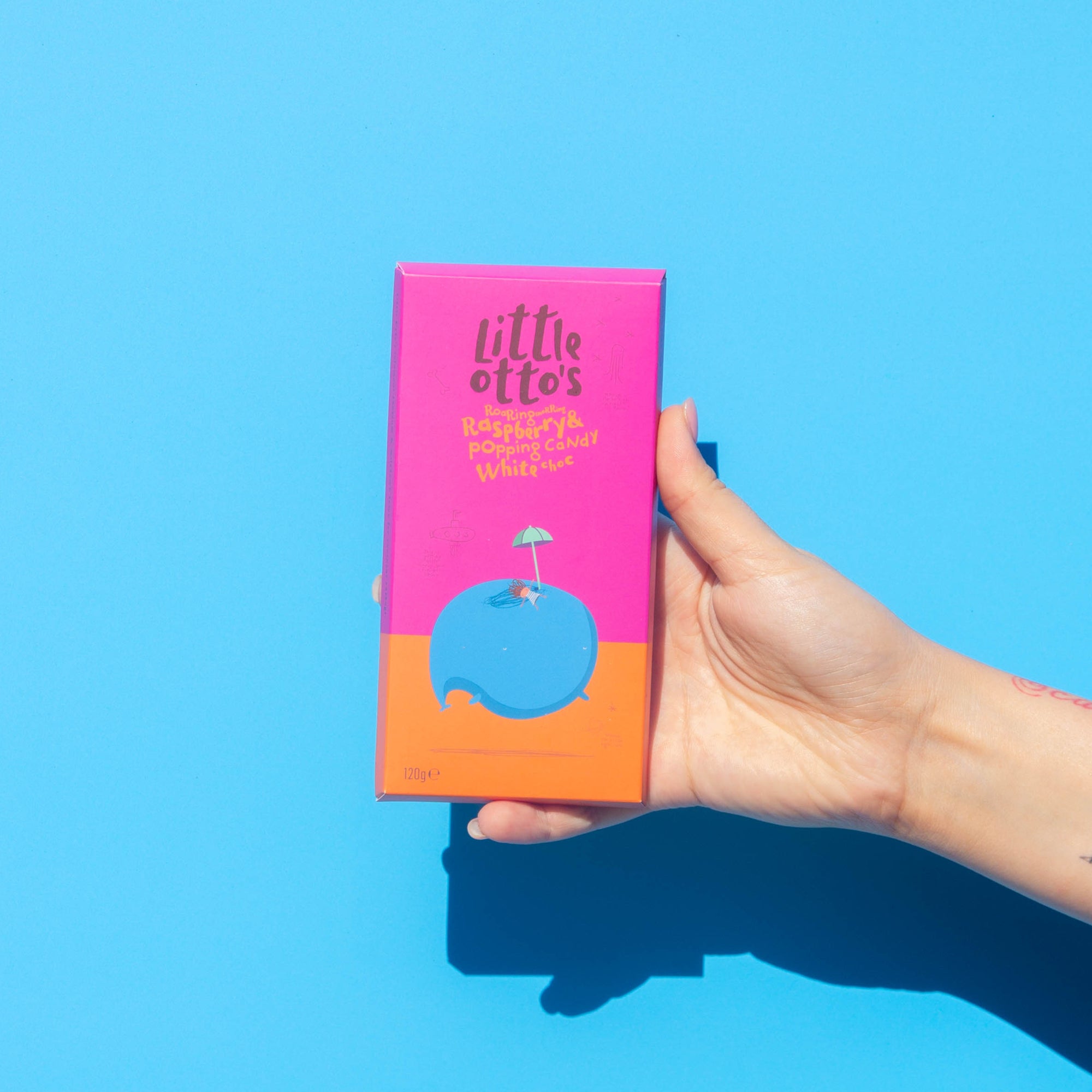 Little Otto's Otto's Chocolate bar White Chocolate Raspberry and Popping Candy Infront of Busselton blue wall