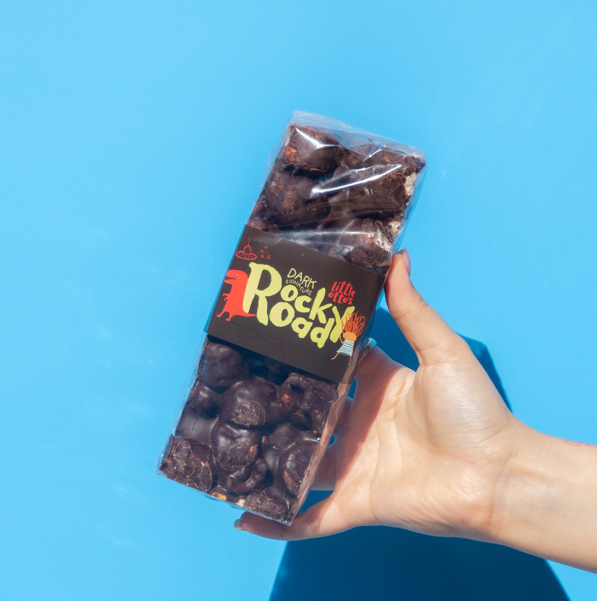 Little Otto's Staff holding Dark Chocolate Signature Rocky Road 500g infront of Busselton blue wall