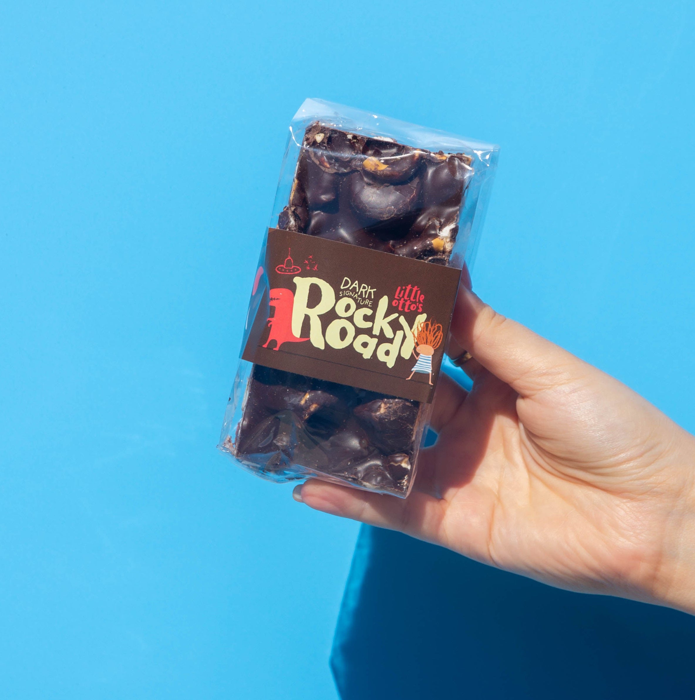 Little Otto's Staff holding Dark Signature Rocky Road 250g infront of Busselton blue wall