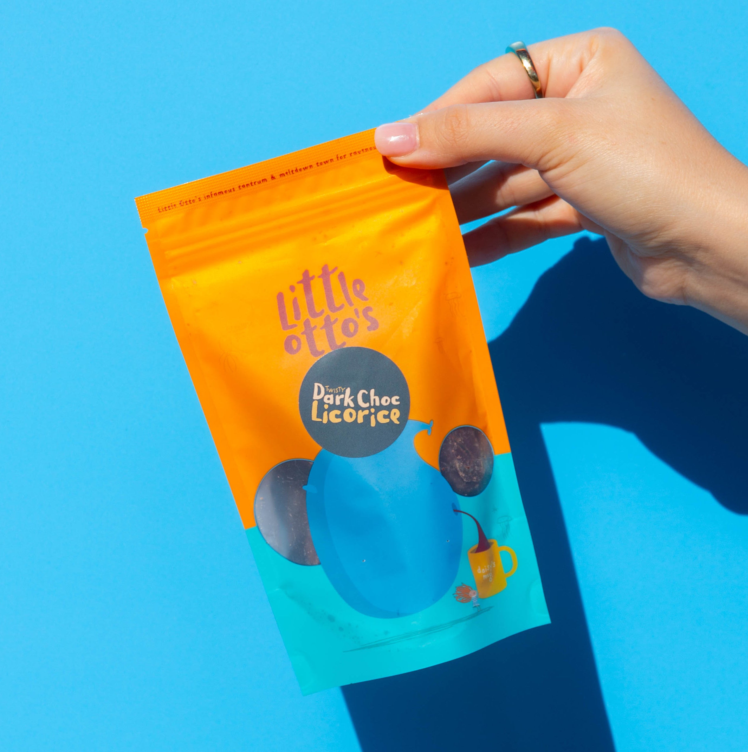 Little Otto's Staff holding Dark choc Licorice infront of Busselton blue wall