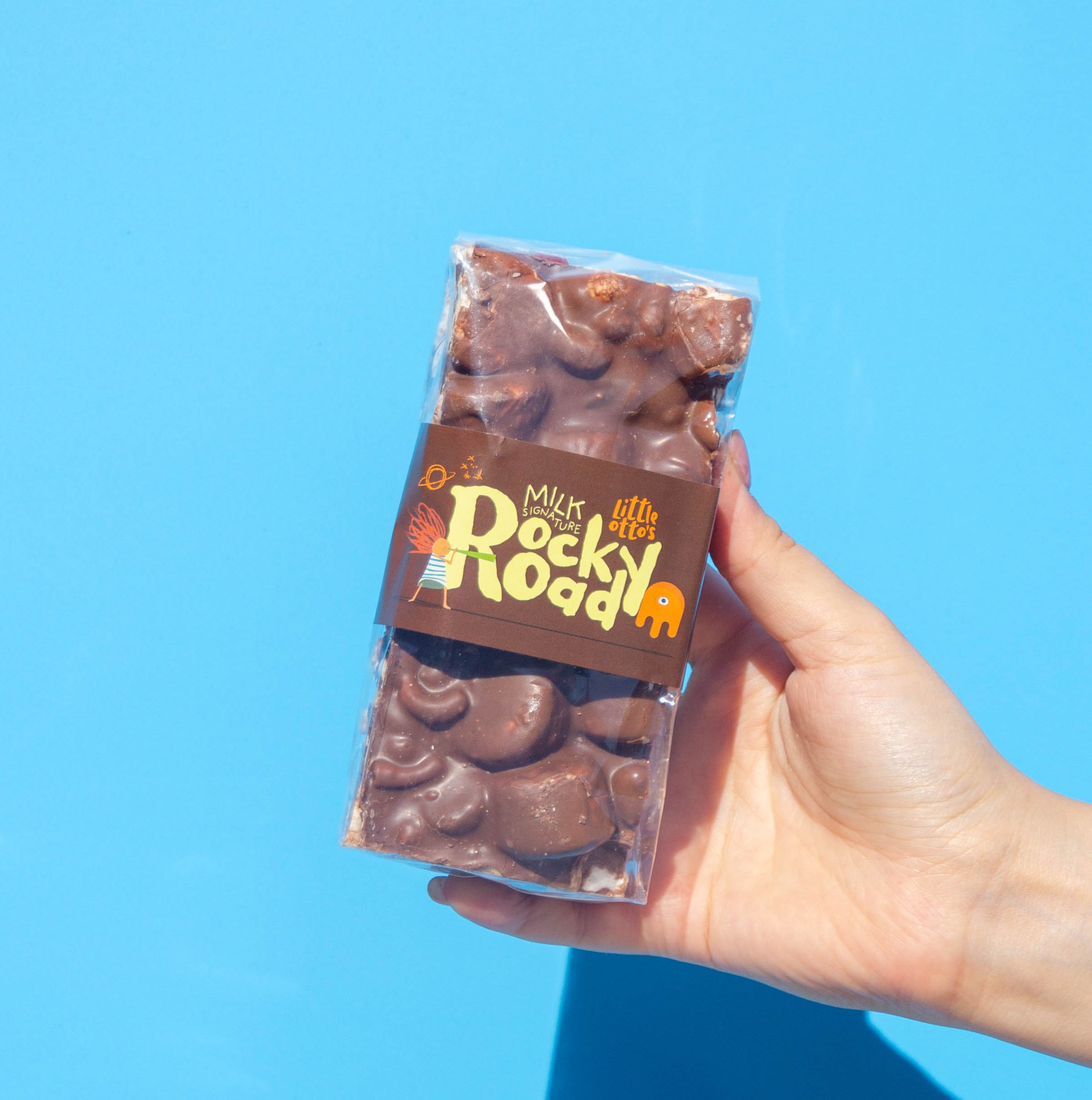 Little Otto's Staff holding Milk Chocolate Signature Rocky Road 340g infront of Busselton blue wall