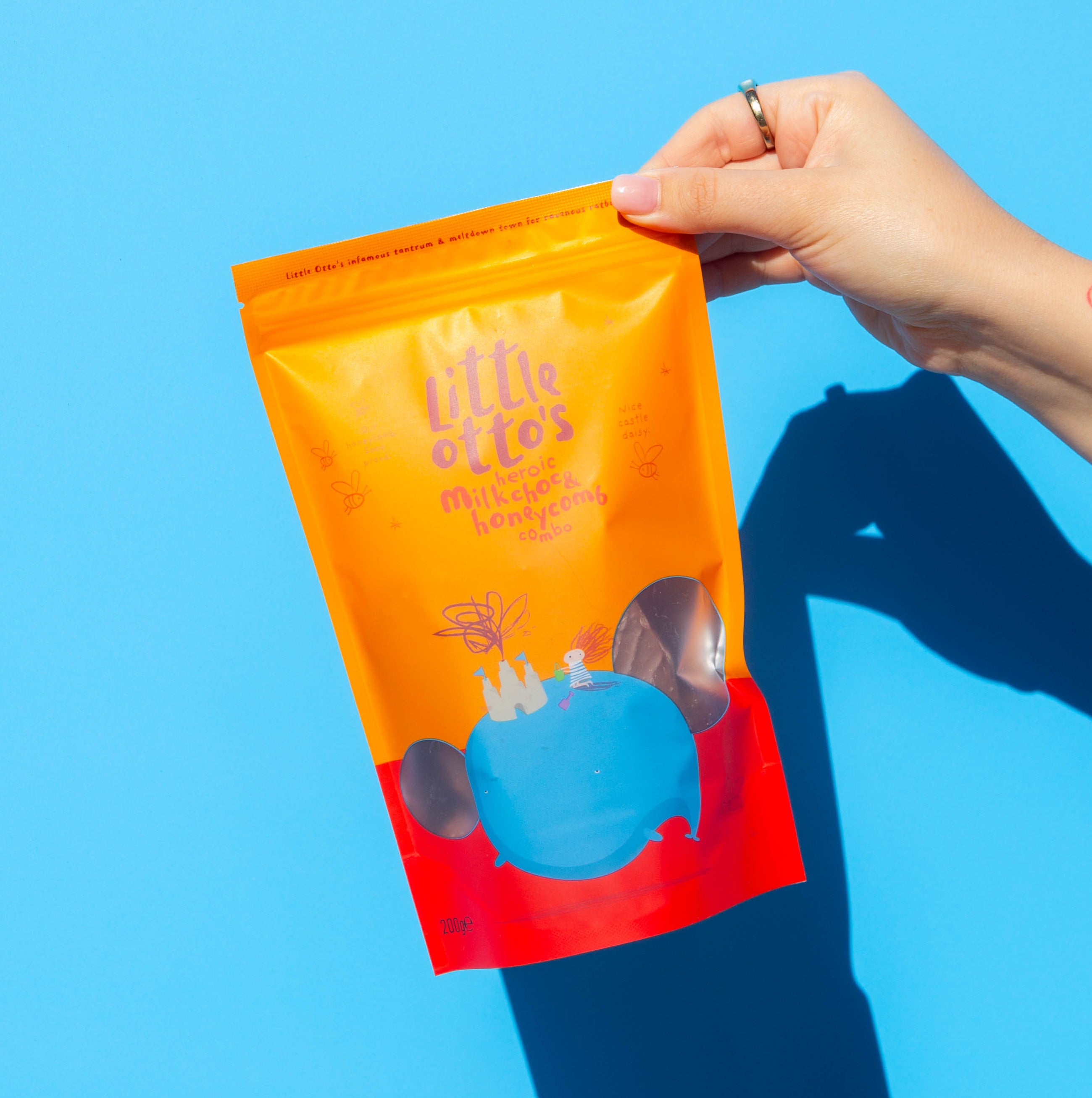 Little Otto's Staff holding Milk choc honeycomb infront of Busselton blue wall