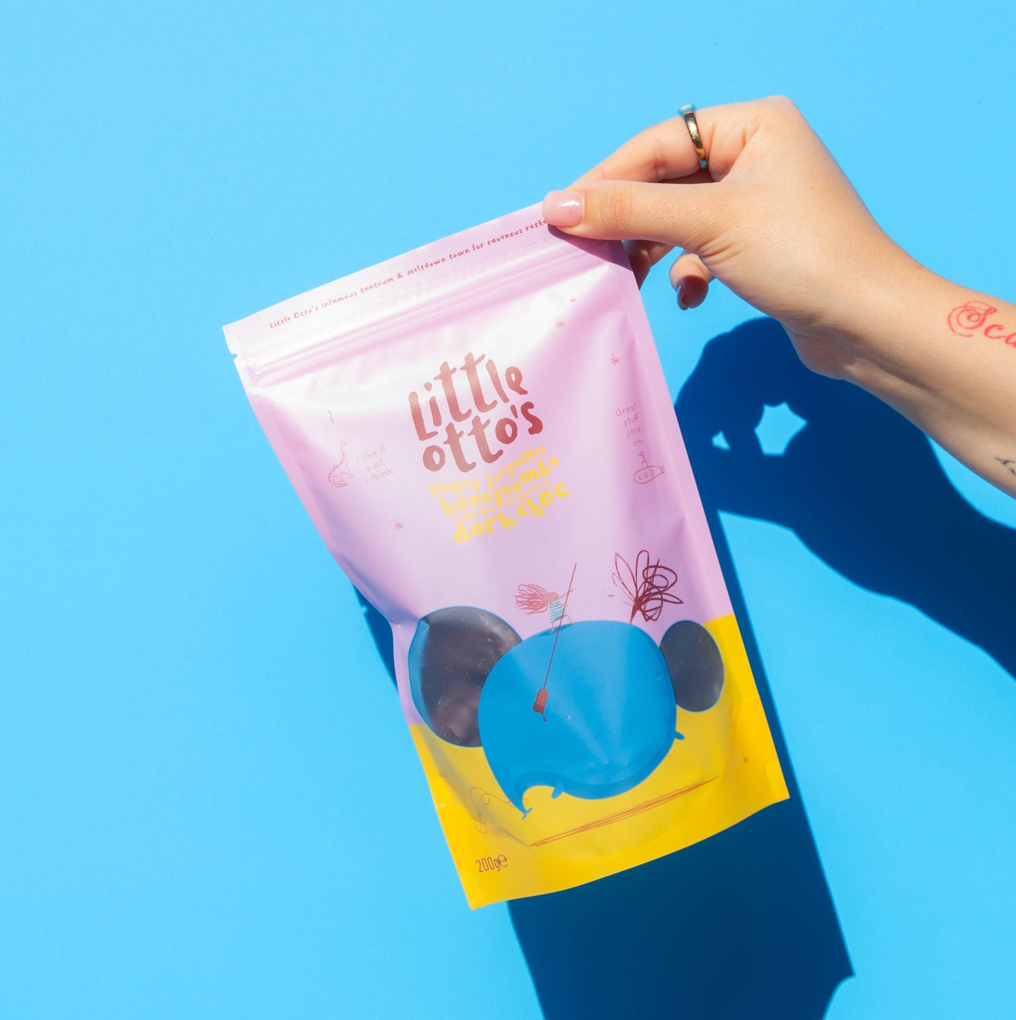 Little Otto's Staff holding dark choc honeycomb infront of Busselton blue wall