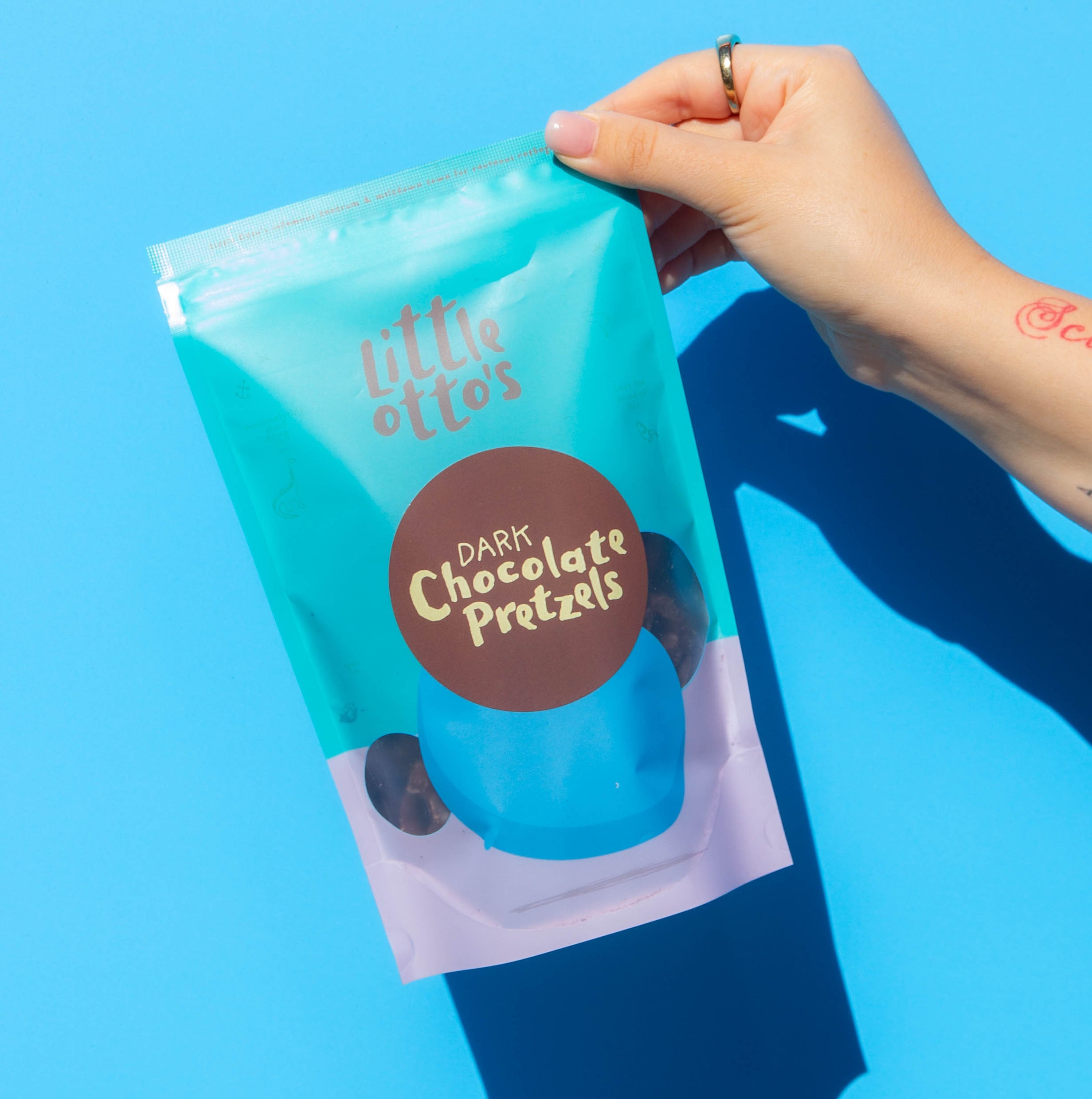 Little Otto's Staff holding dark choc pretzels infront of Busselton blue wall