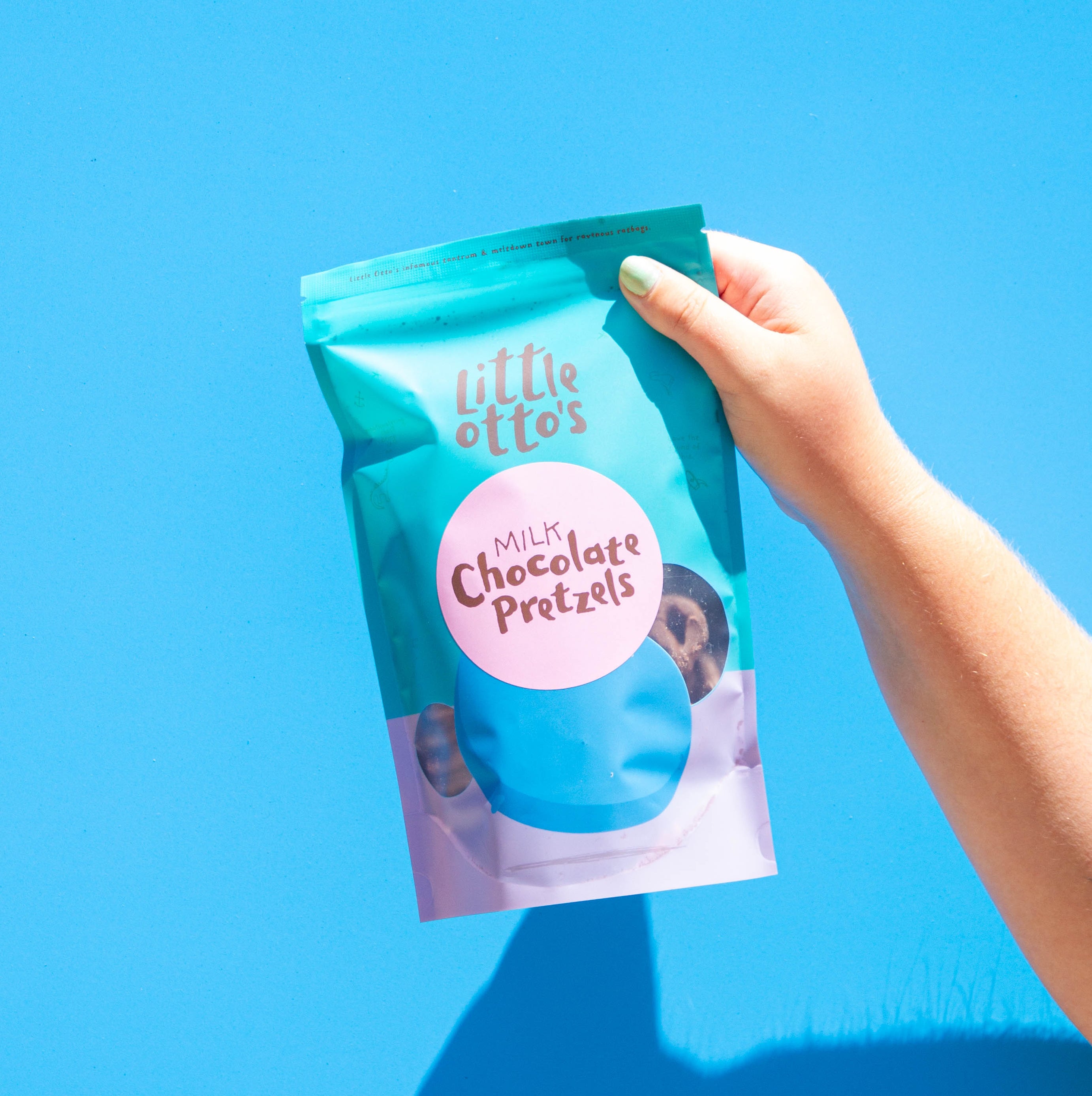 Little Otto's Staff holding milk choc pretzels infront of Busselton blue wall