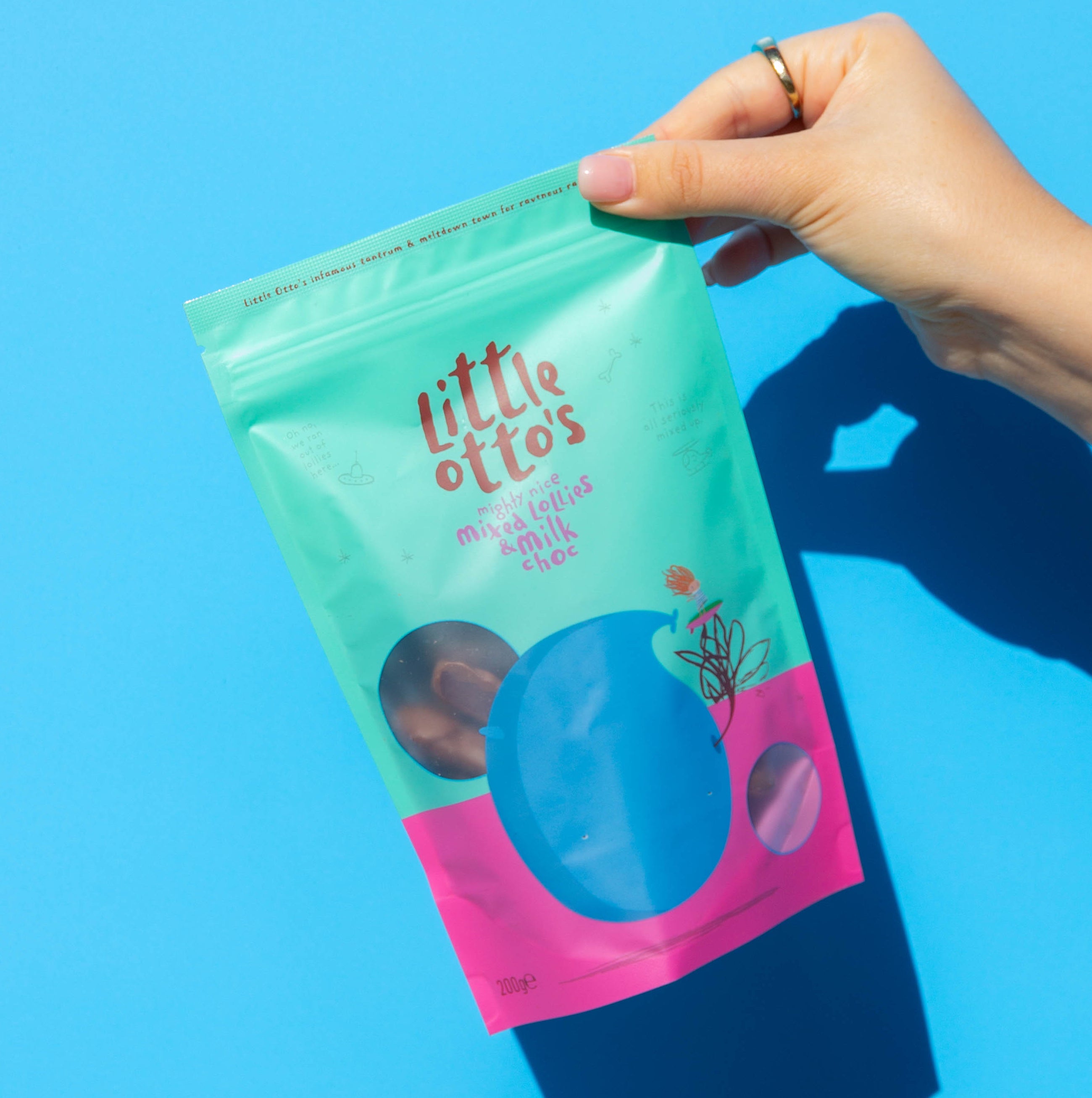 Little Otto's Staff holding mixed lollies and milk choc infront of Busselton blue wall