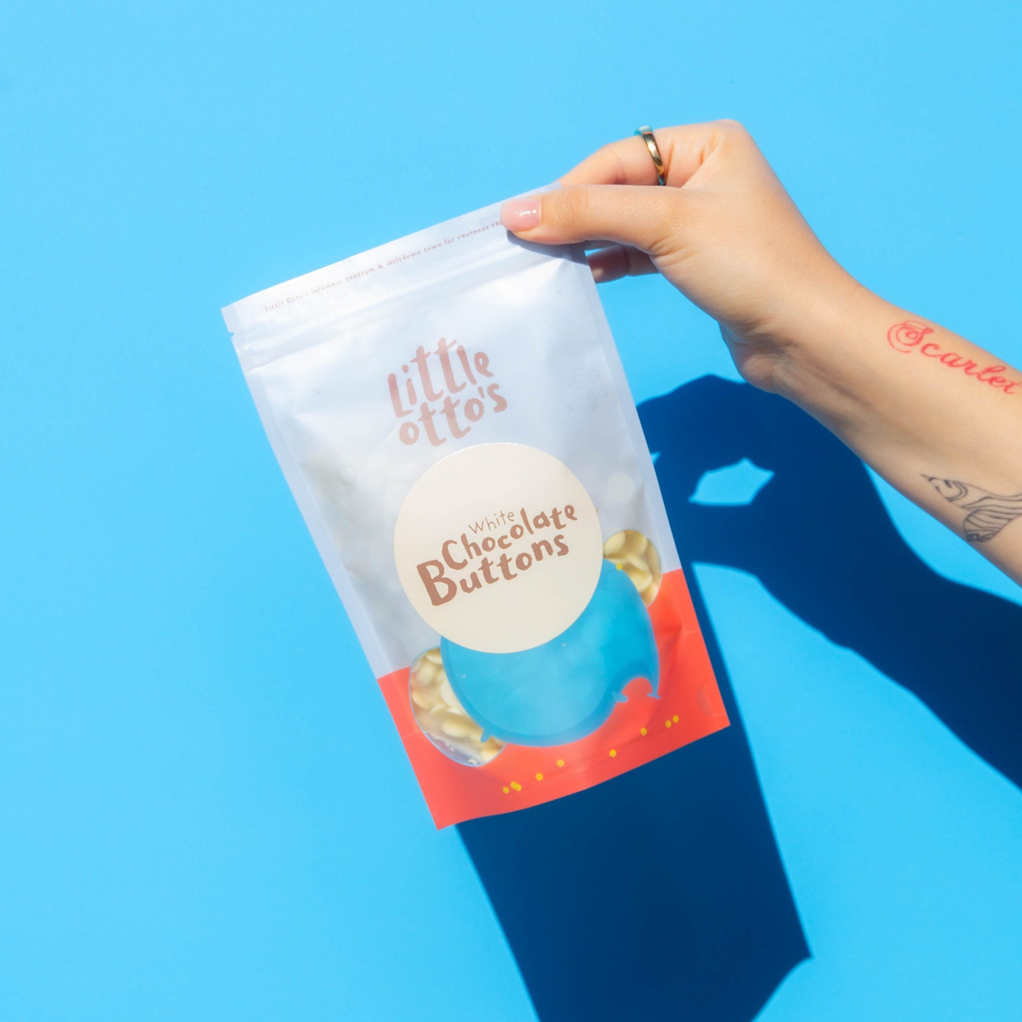 Little Otto's Staff holding White Chocolate Buttons 250g nfront of Busselton blue wall