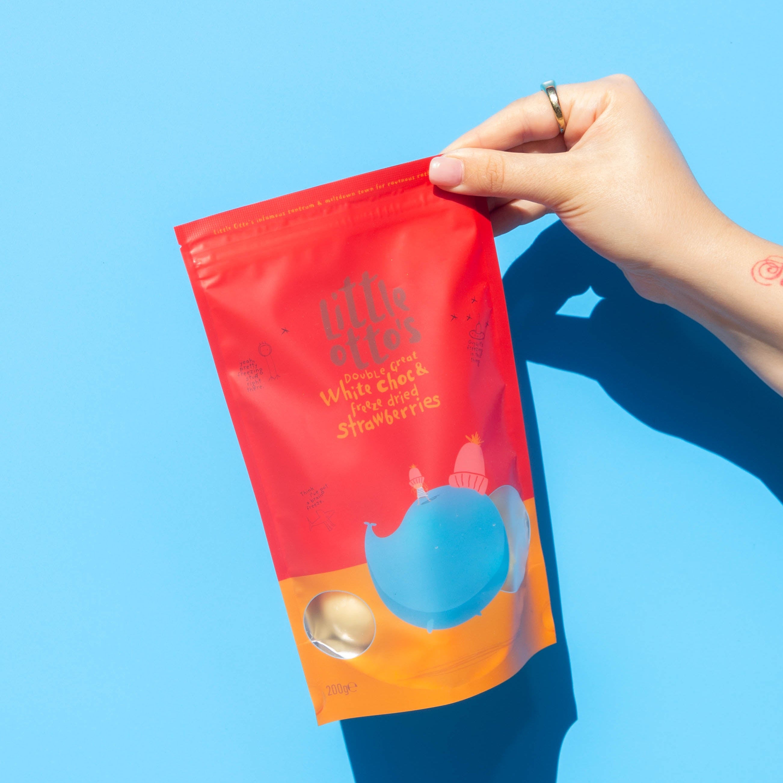 Little Otto's Staff holding White Chocolate Freeze Dried Strawberries 200g infront of Busselton blue wall