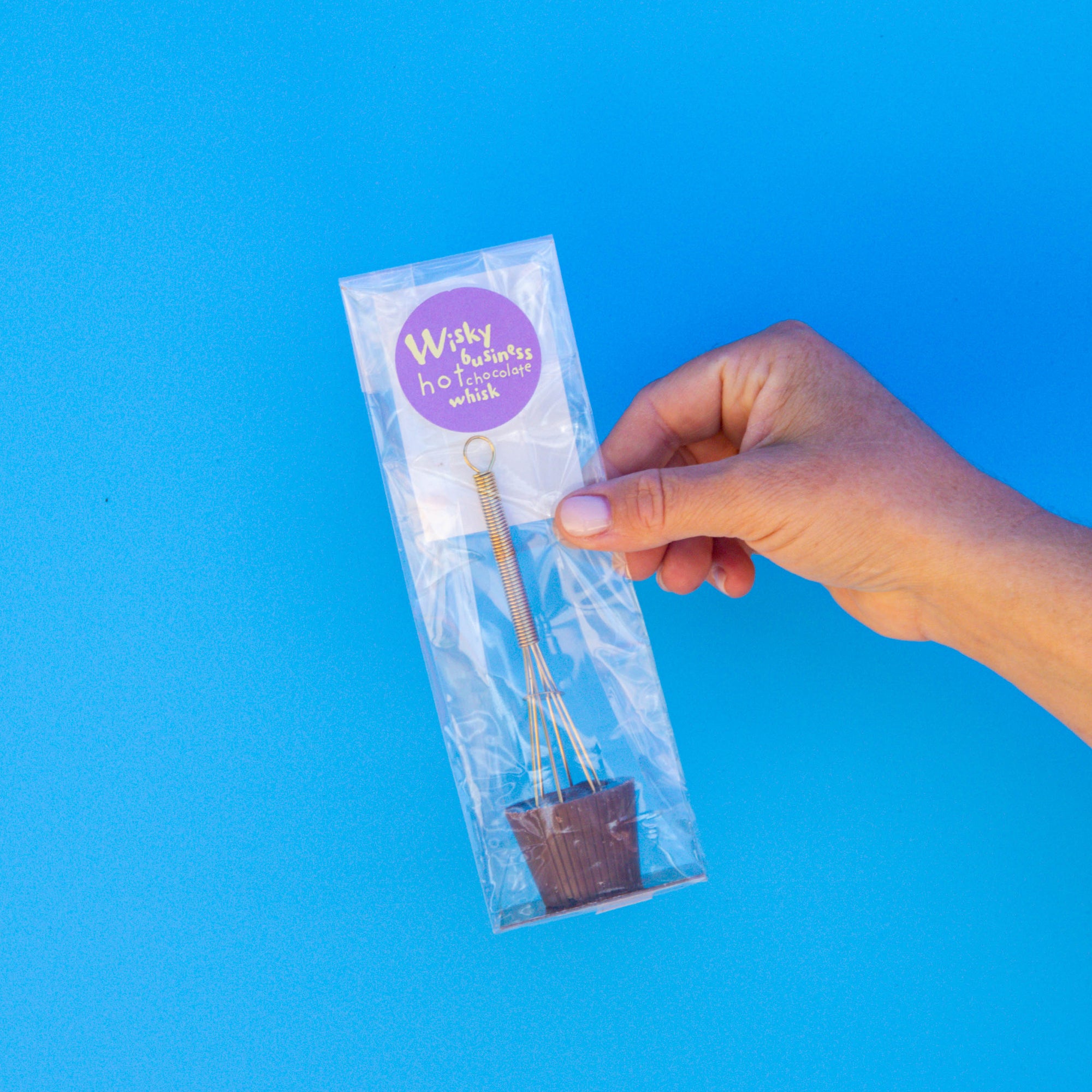 Little Otto's Staff holding Little Otto's Wisky Business Hot Chocolate Whisk Infront of Busselton blue wall