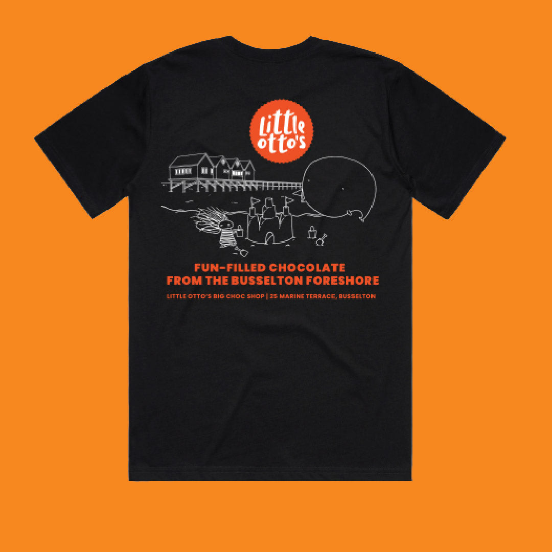 A black short-sleeve t-shirt with a graphic print on the front, featuring a red circular 'little otto's' logo and white line art of a coastal scene with a whale and pier, set against a solid orange background.